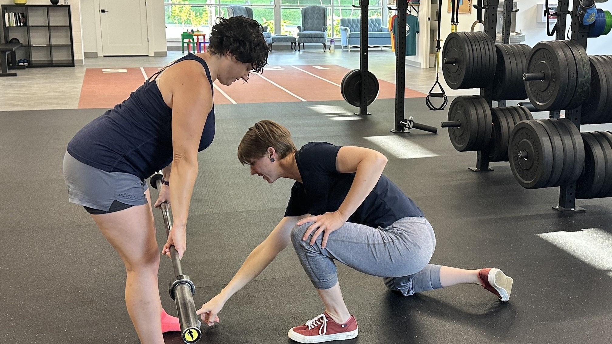 Coach guiding a member through a barbell deadlift setup at The Perfect Squat gym in Indianapolis